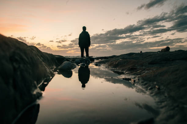 istock Silhouette of a standing man at sunset and reflection 1300336506