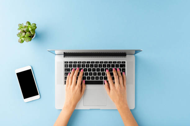 istock Woman’s hands working on laptop on blue table with accessories. Business background. Flat lay 1300337562