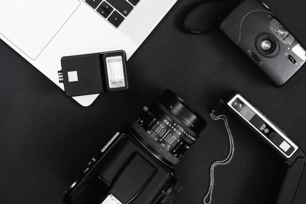istock Workspace concept for photographers, top view of a computer equipment, cameras and flash on black table background. 1300339184