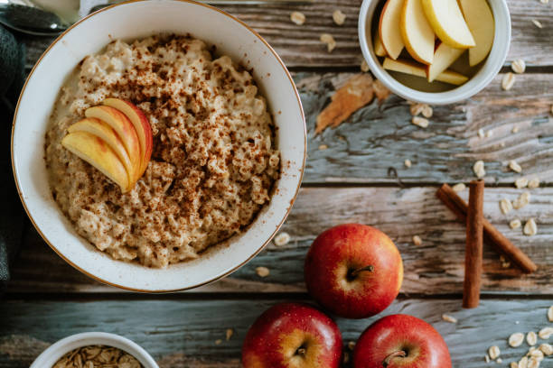 una ciotola di porridge con mele e cannella, natura morta del cibo, colazione sana - porridge foto e immagini stock