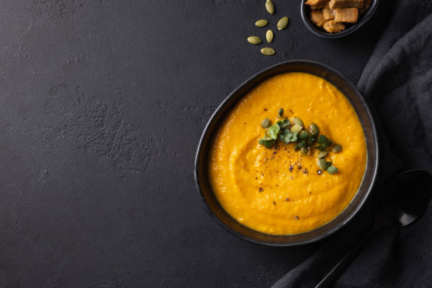 istock Fall pumpkin soup garnish microgreens with ingredients on black background. 1300339650