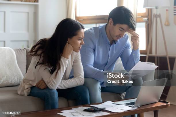 Concerned Young Married Couple Studying Bank Letters Informing About Debt Stock Photo - Download Image Now