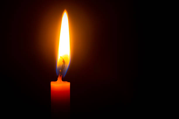 istock Close up single candle light and flame on black background 1300341945