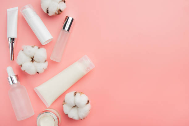 istock Glass and plastic cosmetic bottles on pink background with cotton bolls. Copy-space for text 1300342056