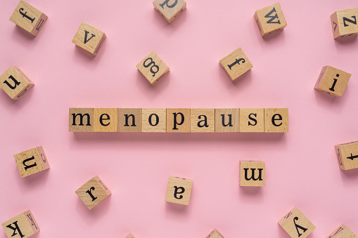 Palabra de la menopausia en bloque de madera. Vista plana sobre fondo rosa claro. photo