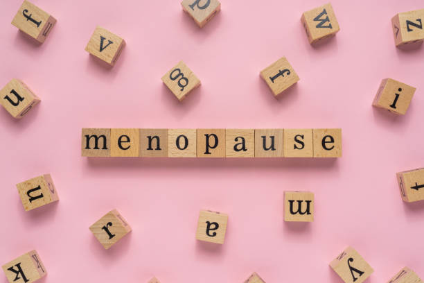 palabra de la menopausia en bloque de madera. vista plana sobre fondo rosa claro. - menopausia fotos fotografías e imágenes de stock