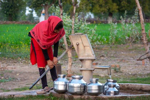неизвестная индийская девушка использует ручной насос для питьевой воды. - groundwater стоковые фото и изображения