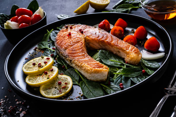 istock Fried salmon steak and fresh vegetables on wooden black table 1300344584