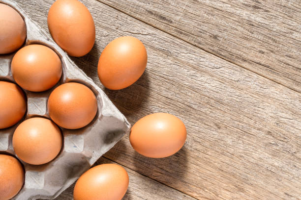 istock Chicken eggs in a cartoon with a copy space on wooden board background. Flat lay. 1300345128