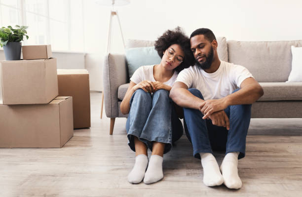 istock Frustrated African Couple Sitting Among Moving Boxes Indoors 1300345266