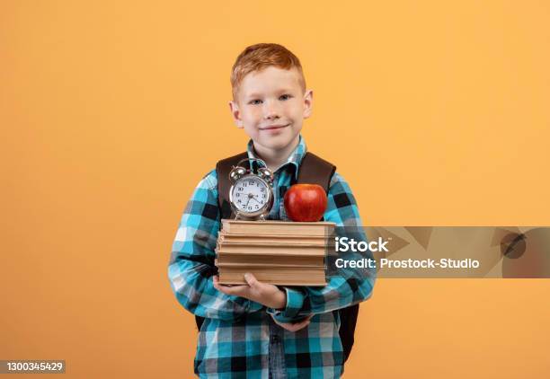 Cheerful Kid With Backpack Holding Book Apple And Watch Stock Photo - Download Image Now