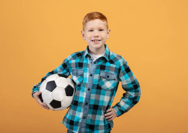 istock Boy posing with soccer ball on yellow 1300346698