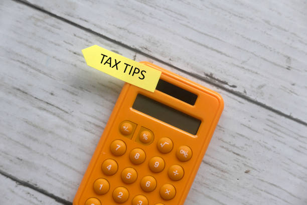 Top view of calculator and sticky note written with Tax Tips on white wooden background. Top view of calculator and sticky note written with Tax Tips on white wooden background. goldco reviews pros and cons stock pictures, royalty-free photos & images