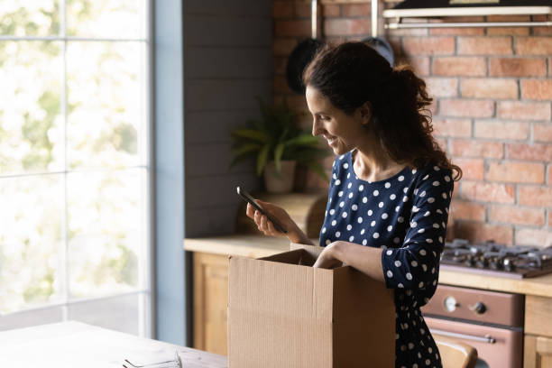 istock Smiling young woman do unpacking track parcel status on cell 1300347612