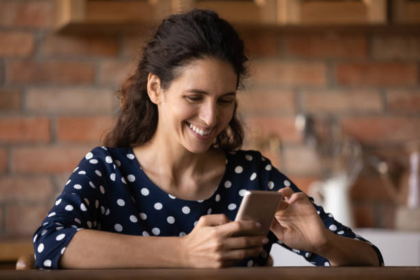 istock Smiling woman look at cellphone screen texting online 1300347634