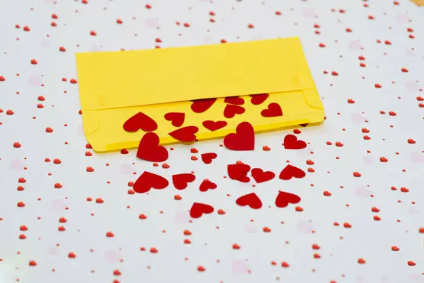 Red little hearts coming out from yellow envelope on valentine day background with copy space, loveletter concept, close-up