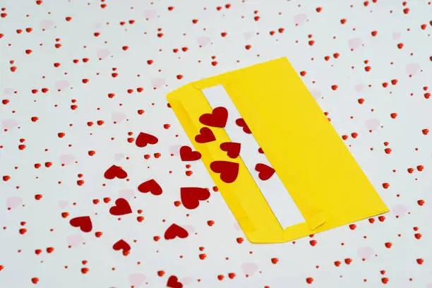 Red little hearts coming out from yellow envelope on valentine day background with copy space, loveletter concept, close-up