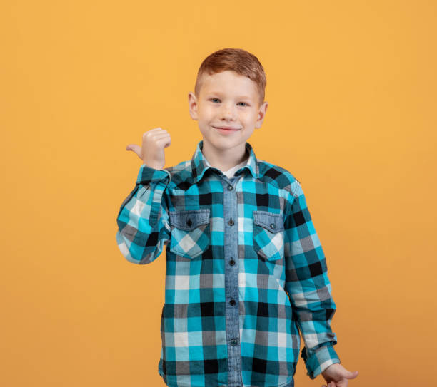 istock Cheerful ginger kid in flannel pointing at copy space 1300351518