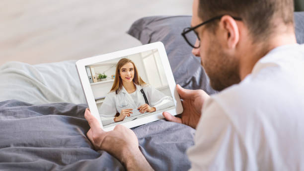 istock Man Having Video Call With Doctor On Digital Tablet While Lying In Bed 1300351707