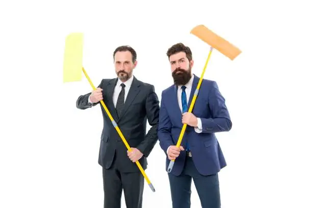Photo of Cover our tracks before someone find out financial fraud. Clear reputation. Bearded men formal suits hold mops. Big cleaning day. Cleaning business. Household duties. Cleaning service concept