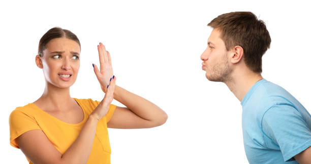 Man trying to kiss confused woman rejecting him Stay Away From Me. Profile portrait of young couple, guy in love reaching and trying to kiss confused woman, lady rejecting him and showing stop sign gesture, isolated over white studio background stop gesture photos stock pictures, royalty-free photos & images