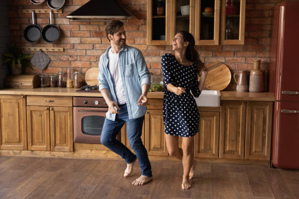 istock Overjoyed couple have fun dancing in home kitchen 1300355198