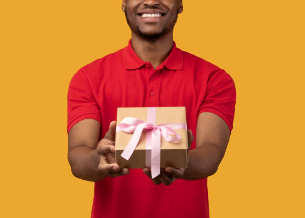 istock Black guy holding gift box showing to camera 1300357040