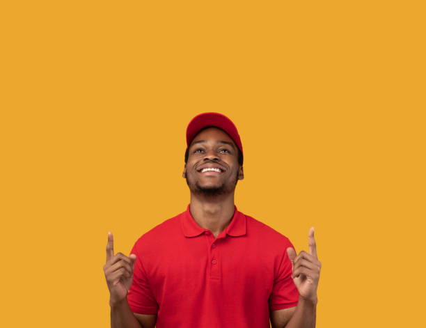 istock Smiling black bearded delivery man pointing up 1300357110