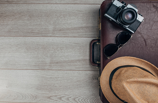 Hat, suitcase, camera and sunglasses on wooden background. Top view. Flat lay concept.
