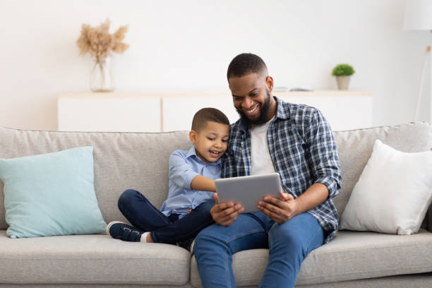 istock Young Black Father And Little Son Using Tablet At Home 1300357311