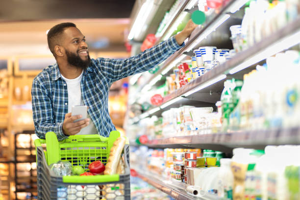 schwarze männliche shopping-lebensmittel im supermarkt nehmen produkt aus dem regal - color image food dairy product people stock-fotos und bilder