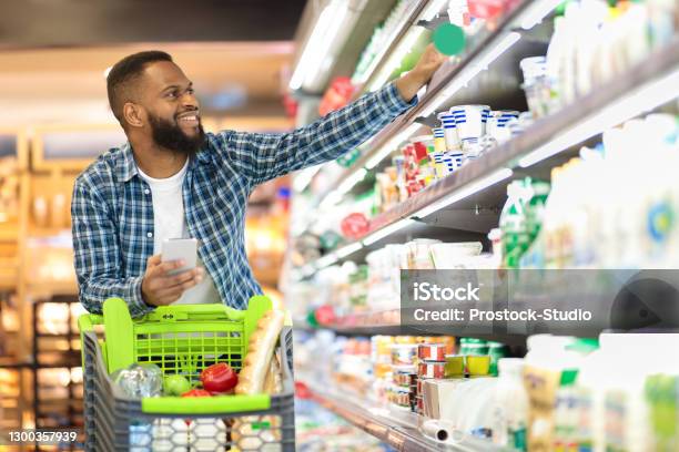 Black Male Shopping Groceries In Supermarket Taking Product From Shelf Stock Photo - Download Image Now