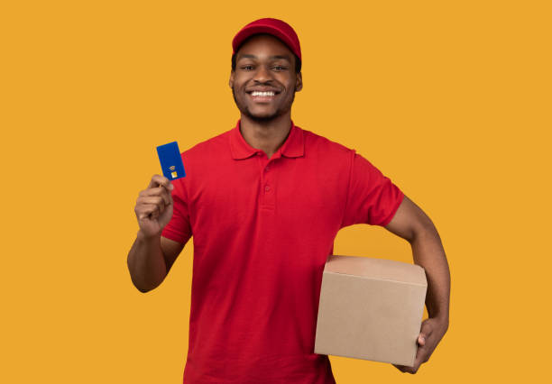 istock Black delivery man holding credit card and box 1300357942