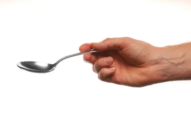 Hand holds a spoon on a white background.