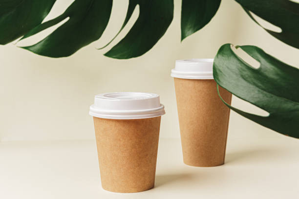 istock Disposable paper coffee cup and green leaf 1300361120