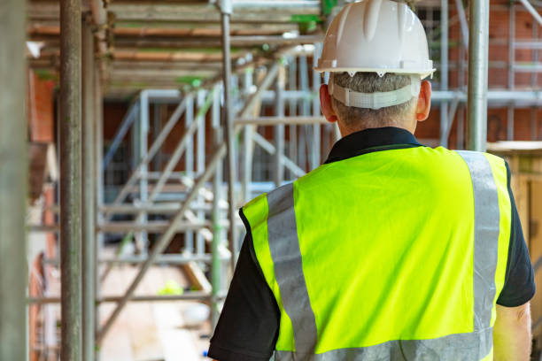istock Rear view of male builder construction worker or builder on building site wearing hard hat and hi-vis vest 1300361332