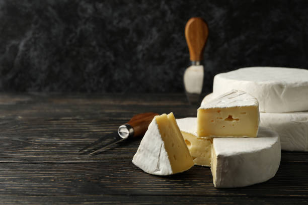 istock Camembert cheese and knives on wooden background, space for text 1300362421