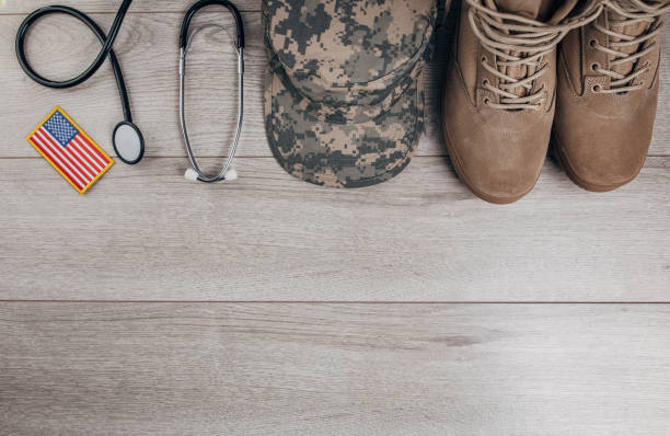 US military doctor equipment Top view of camouflaged military cap, stethoscope, US flag and boots on wooden background. Flat lay concept. usa flag shoes stock pictures, royalty-free photos & images