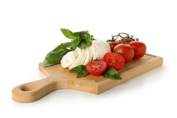 istock Board with mozzarella cheese, tomato and basil isolated on white background 1300362840
