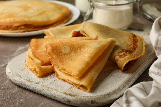 istock Concept of tasty breakfast with thin pancakes on gray table 1300364371