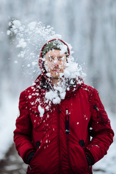 Nobody likes getting hit by a snowball Young man getting hit by a snowball while walking in a forest snowball stock pictures, royalty-free photos & images