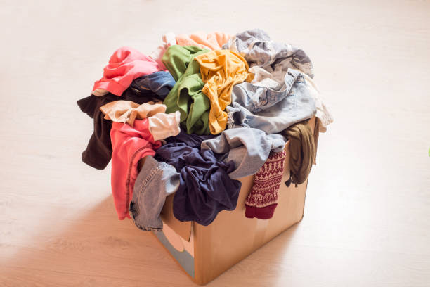istock Pile of clothes in a large cardboard box. Sorting wardrobe and decluttering 1300366757