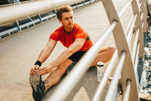 Man stretches legs while sitting on the track after running