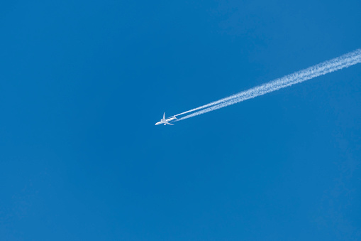 Stunning view of a commercial airplane forming contrails on a blue sky.