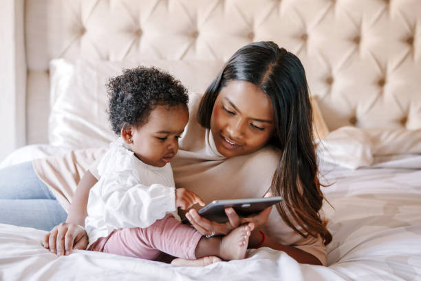 raza mixta madre negra india con niña pequeña viendo dibujos animados en una tableta. diversidad étnica. madre de familia con niño usando tecnología. videochat, videollamada. comunidad de negros. - common family new togetherness fotografías e imágenes de stock