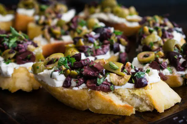 Appetizer made of olive tapenade and goat cheese spread on toasted ciabatta bread