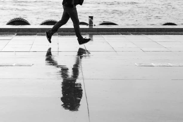 Silhouette in blurred motion of man walking his dog in black and white.
