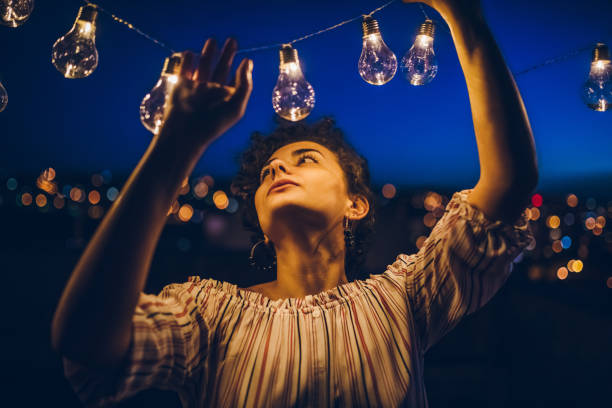 istock Young lonely woman with string light on rooftop 1300384970