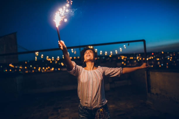 istock Young woman with sparkler on rooftop 1300384995