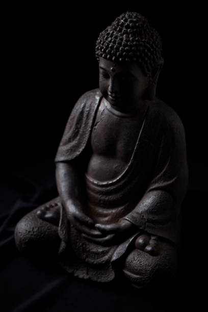 istock Meditating Buddha Statue isolated on black background. 1300386002